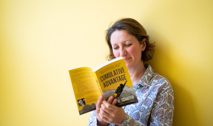 Woman reading book against a yellow background