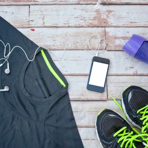 A collection of walking equipment including walking shoes, a t-shirt, a waterbottle, and a phone with earbuds.