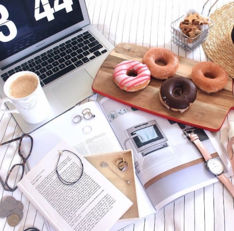 Donuts by a laptop and a stack of papers.