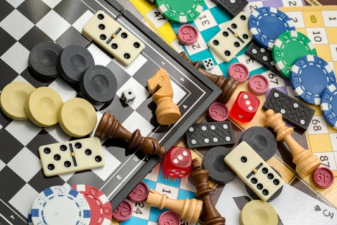 A chess board laden with dominoes, poker chips, and various chess pieces.