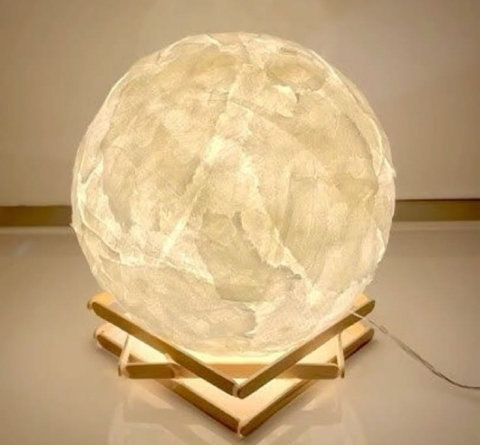 A lamp made of tissue paper, designed to resemble the moon.
