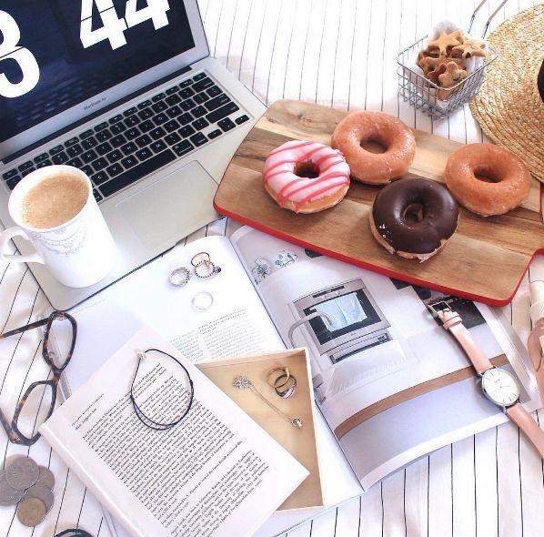 Donuts by a laptop and a stack of papers.