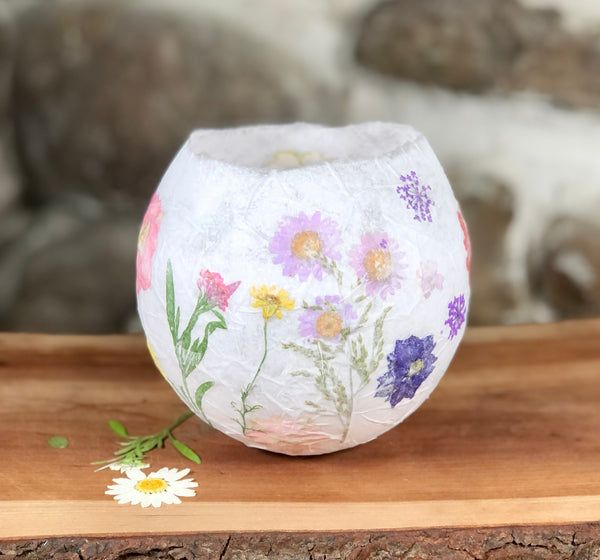 A small paper lantern made with pressed flowers embedded into it.