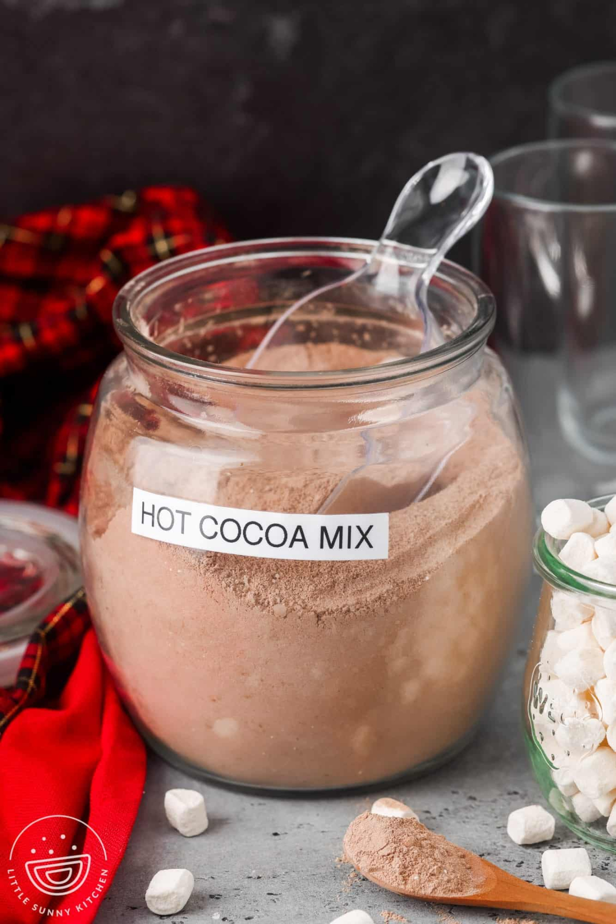 A jar filled with hot cocoa mix with a scoop in it.